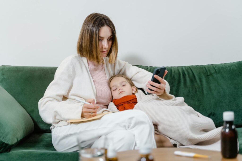 a woman on phone and a child sleeping on a couch